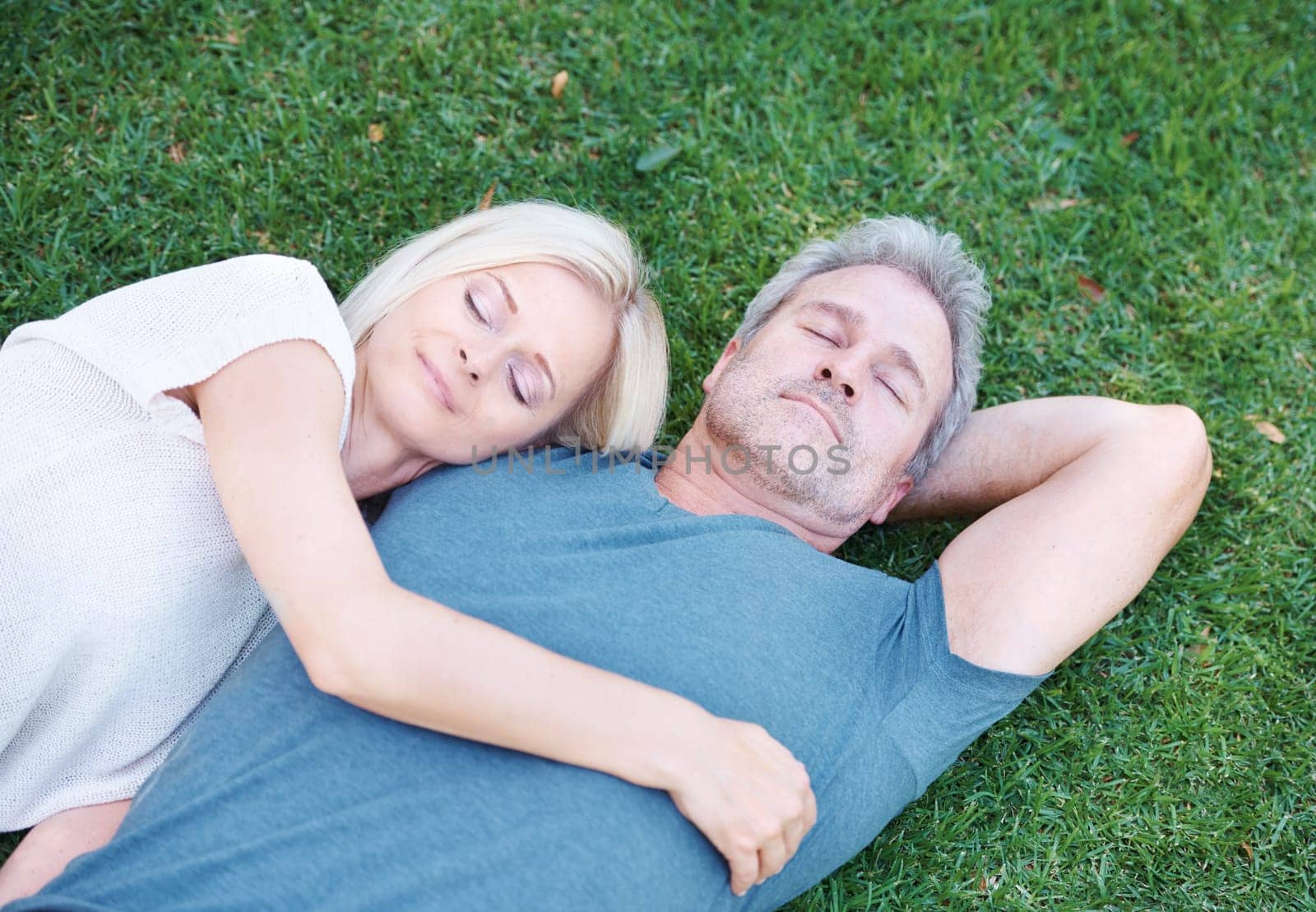 Happy couple, relax and sleeping on grass field with love for embrace, care or support in nature. Top view of man and woman asleep on lawn above with hug for cuddle or relaxation in outdoor romance.