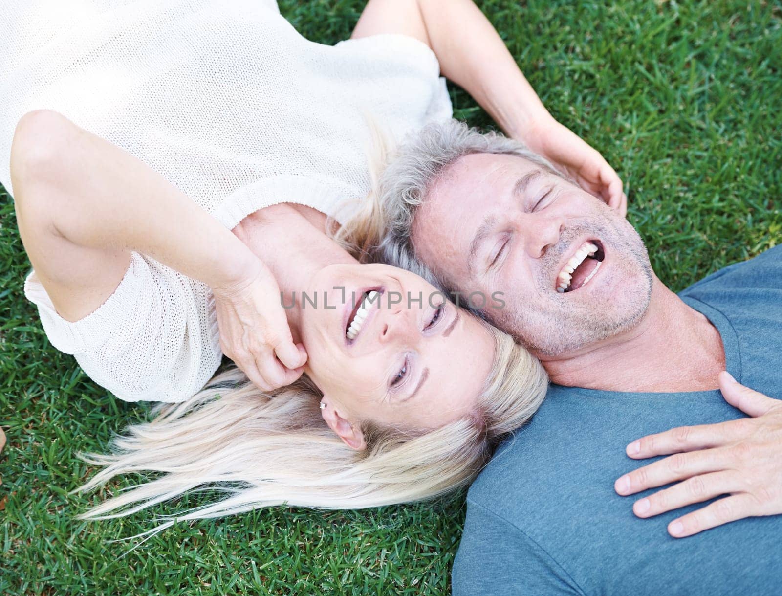 Man, woman and mature or laughing outdoor on grass field for funny joke or comedy, connection or top view. Happy couple, relax and backyard in Australia for relationship bonding, nature or together by YuriArcurs