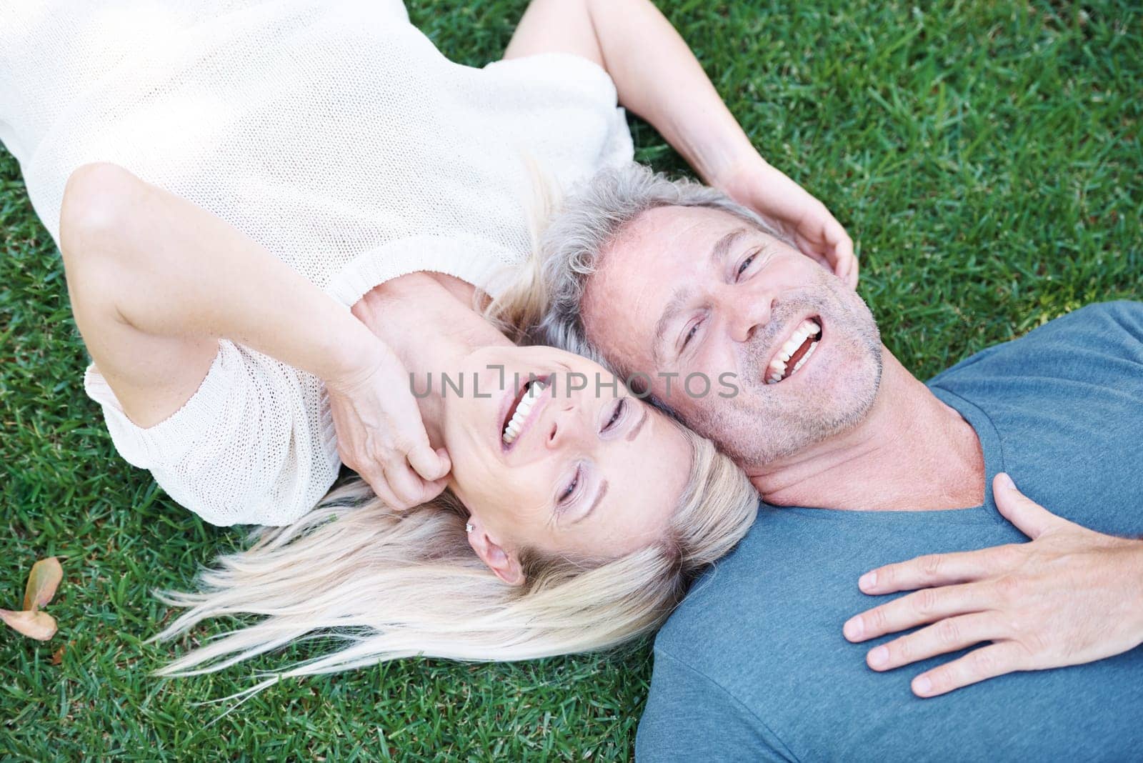 Man, woman and mature or laughing in nature on grass field for funny joke or comedy, connection or top view. Happy couple, relax and backyard in Australia for relationship bonding, park or marriage.