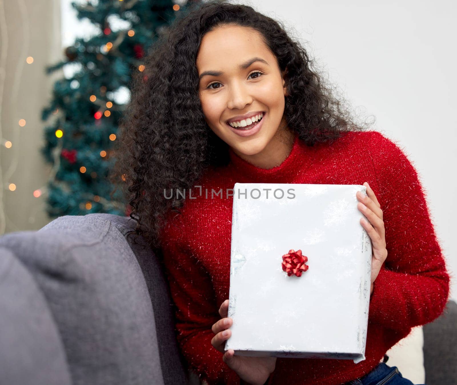 Woman, home and Christmas present in portrait, guess and surprise for Christian holiday celebration. Festive, packaging and gift giving for xmas, winter and vacation with excited in living room by YuriArcurs