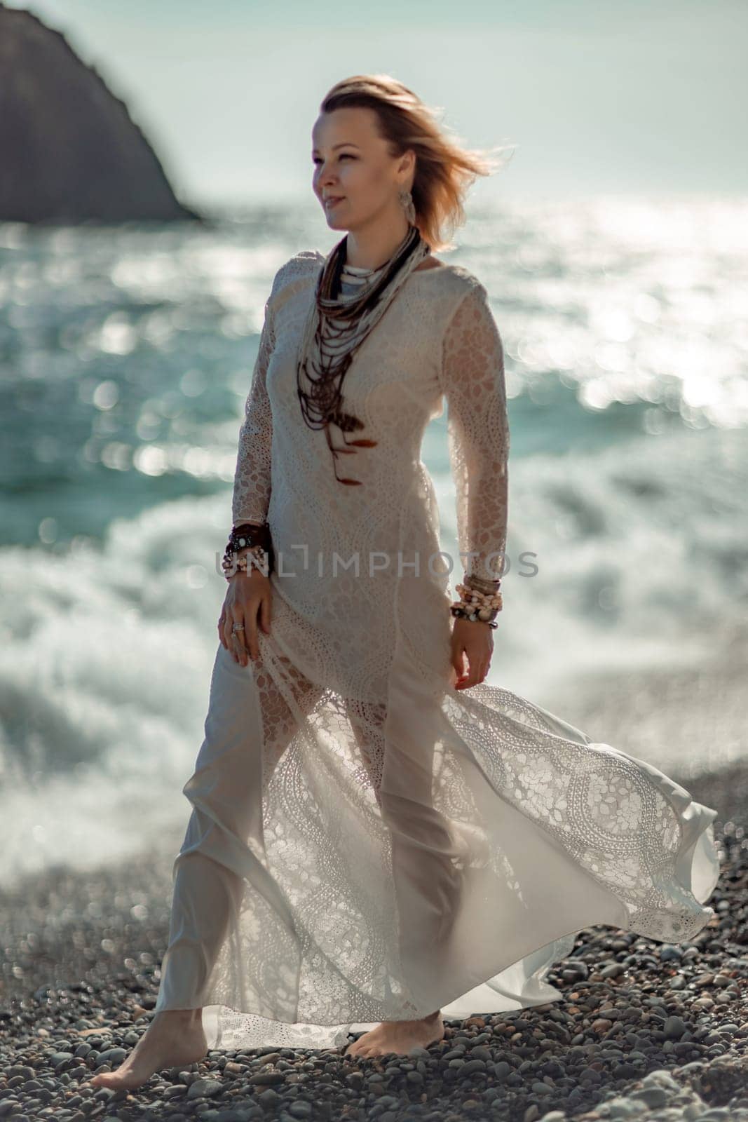 Woman beach sea white dress. The middle-aged looks good with blonde hair, boho style in a white long dress with beach decorations on the neck and arms. by Matiunina