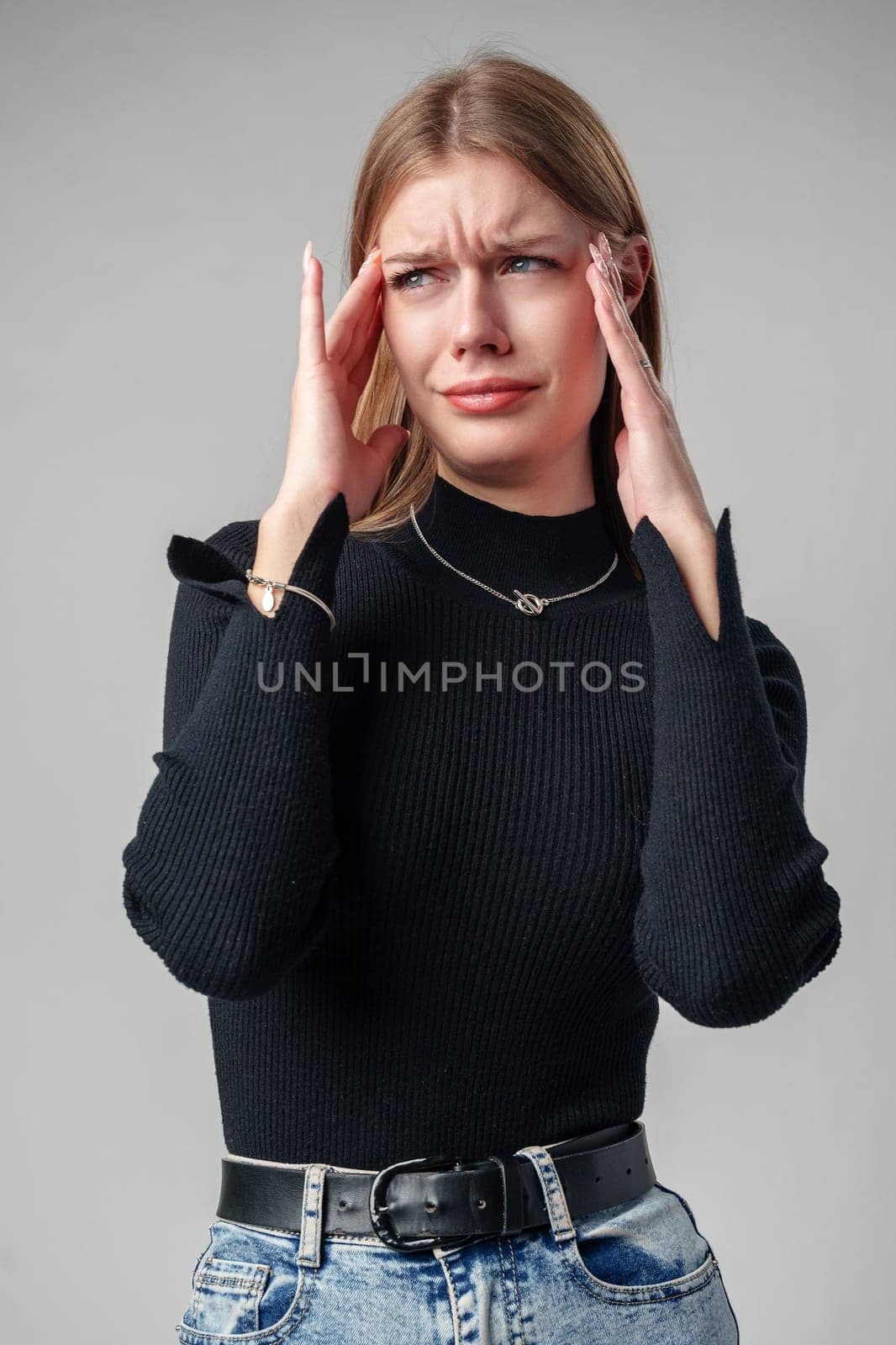 Young Woman In Black Shirt Expressing Discontent Against Grey Background close up
