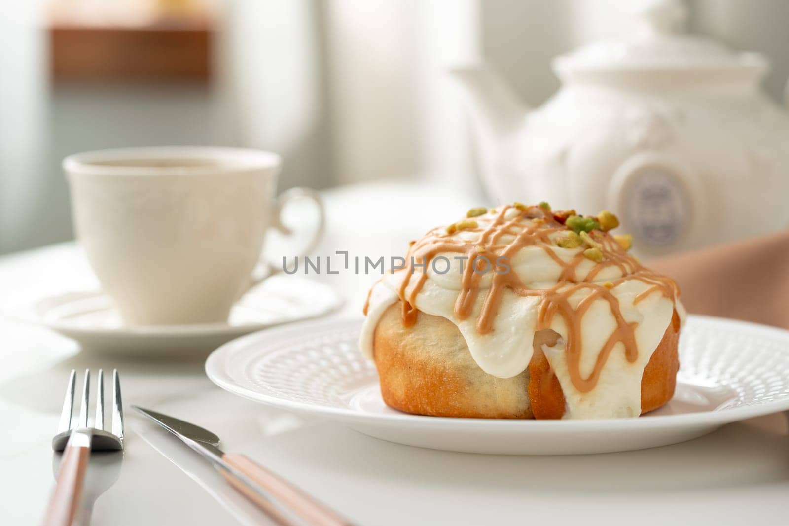 Cinnamon roll bun with icing on plate by Fabrikasimf