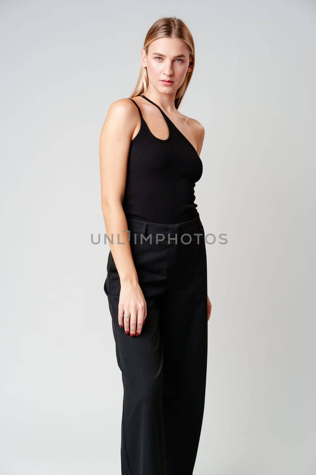 Young Woman Model in Black Top and Pants Posing on gray background in studio