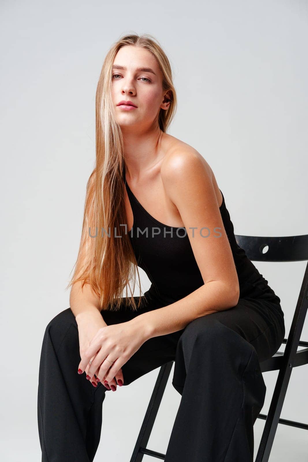 Young Woman Sitting on Chair Posing for Picture in studio
