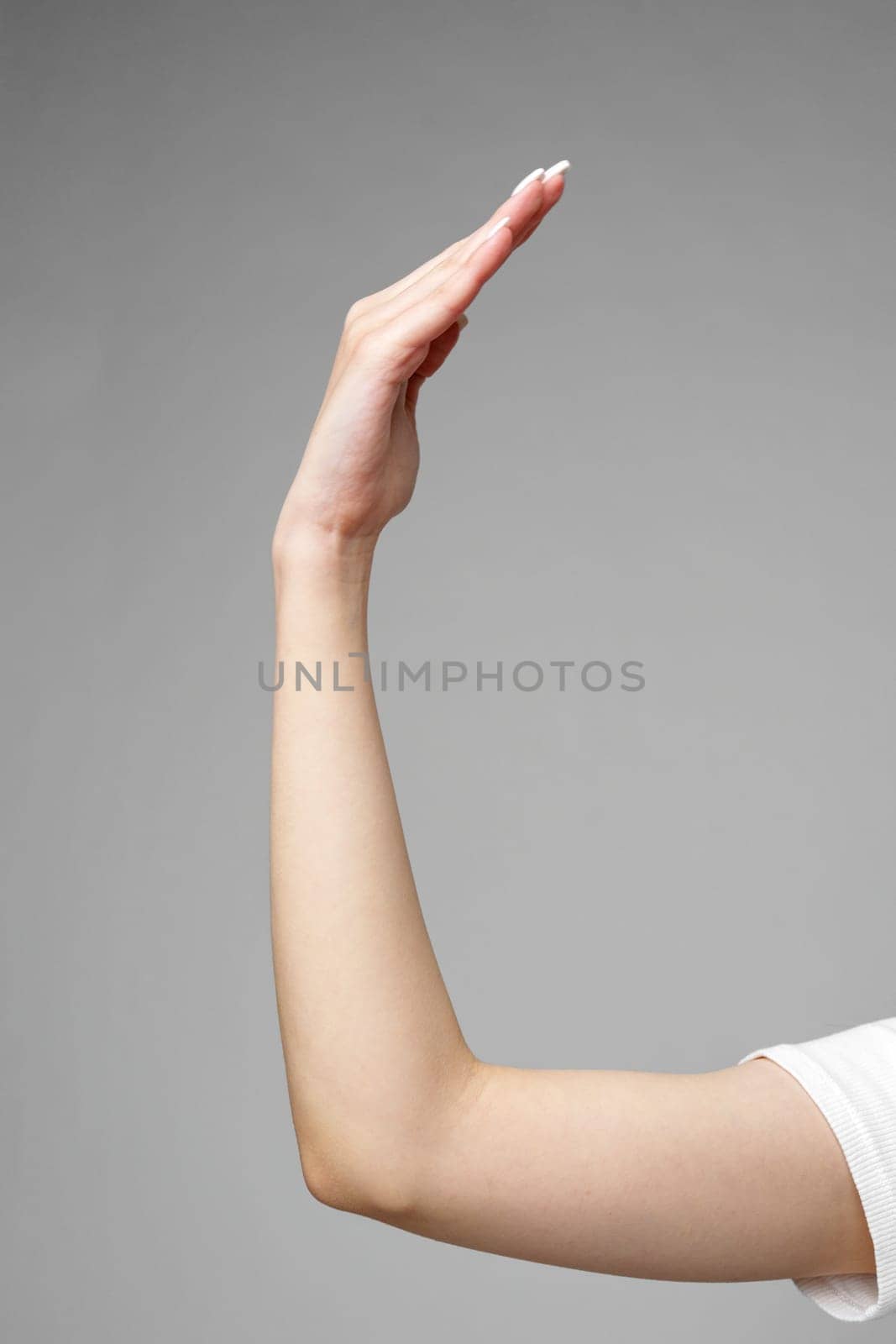 Female hand gesturing sign against gray background close up