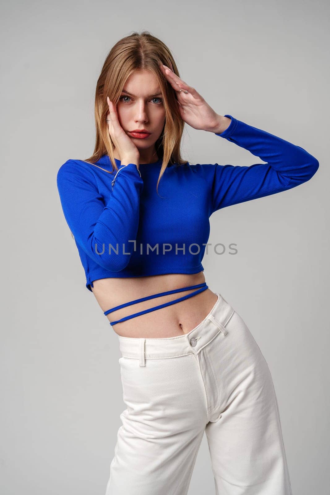 Young Woman model in Blue Top and White Pants posing on white background by Fabrikasimf
