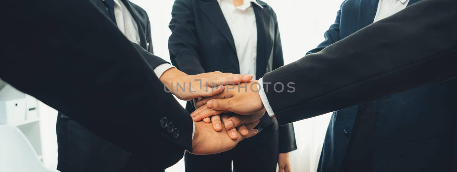 Office worker team stacking hand together symbolize successful group of business partnership and strong collective unity teamwork in community workplace in panoramic banner. Shrewd