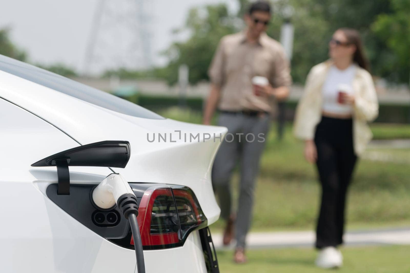 Young couple put EV charger to recharge electric car battery. Expedient by biancoblue