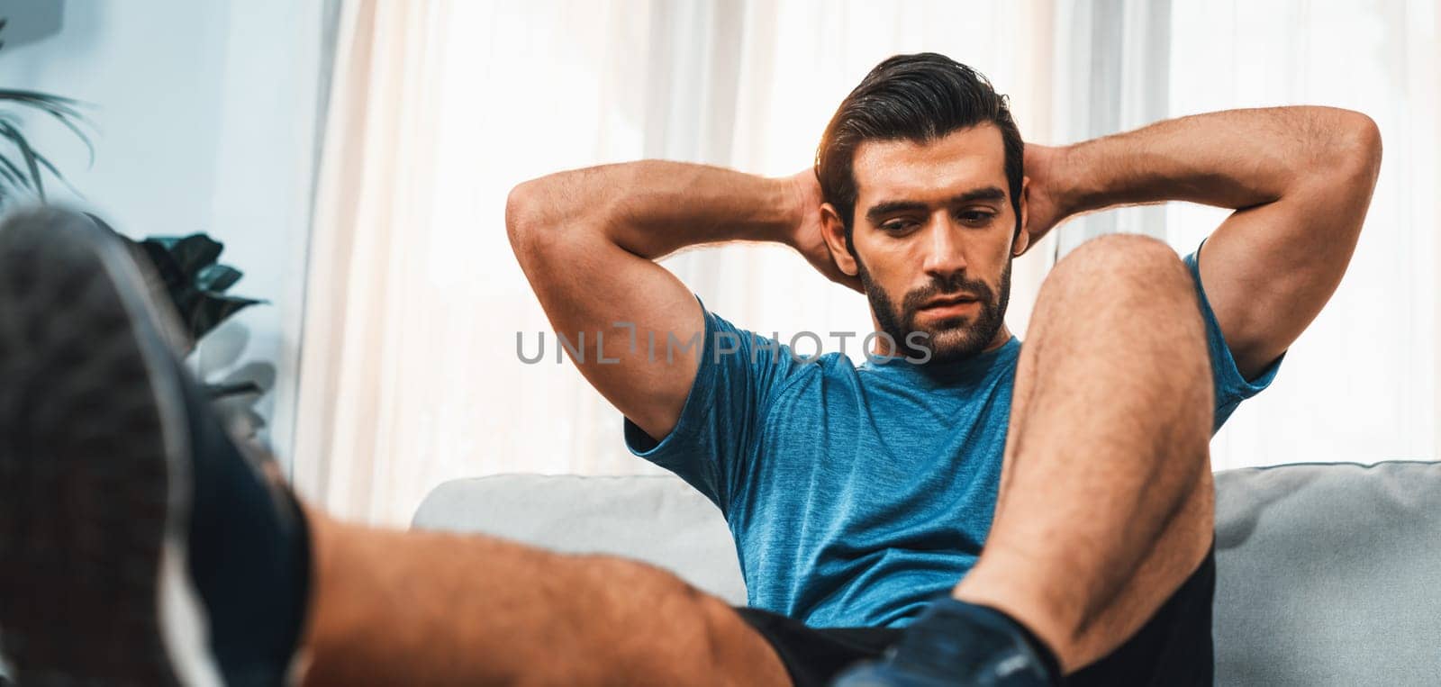 Athletic body and active sporty man using furniture for effective targeting muscle gain exercise at gaiety home exercise as concept of healthy fit body home workout lifestyle.