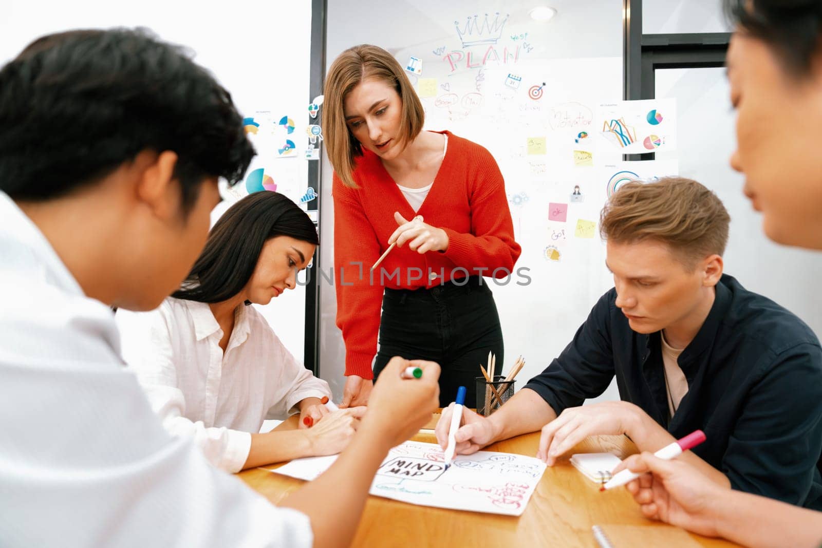 Happy cooperative multi-ethnic business group brainstorming discussion about marketing plan by using mind map in front of glass board with colorful sticky notes at meeting room. Immaculate.