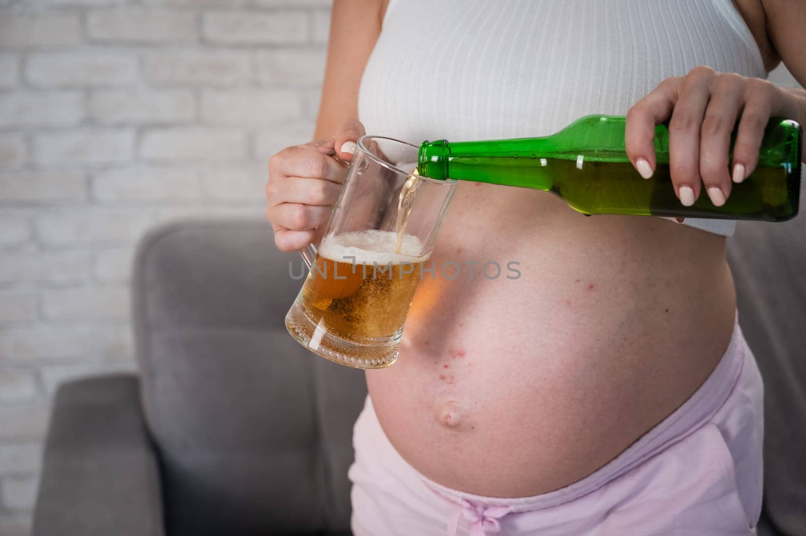 Faceless pregnant woman pouring beer into a glass. by mrwed54