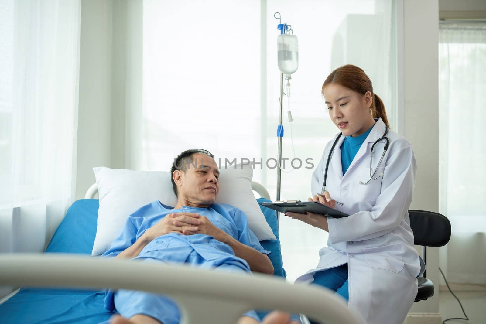 A female doctor is examining the body and taking notes on a sick person in a hospital examination room. by wichayada