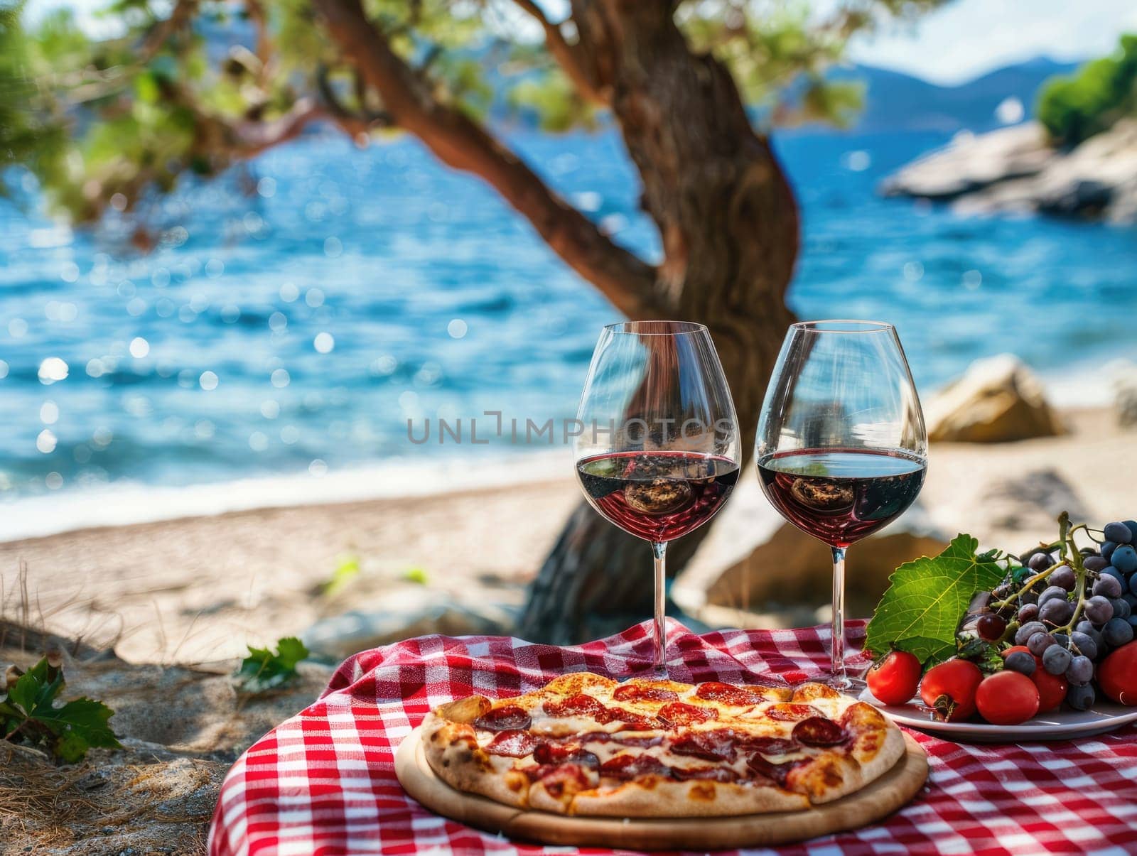 Seaside picnic with red wine in glasses, pepperoni pizza, and fresh grapes on checkered blanket. Romantic outdoor dining concept with a sea view and natural setting. Ai generation. High quality photo