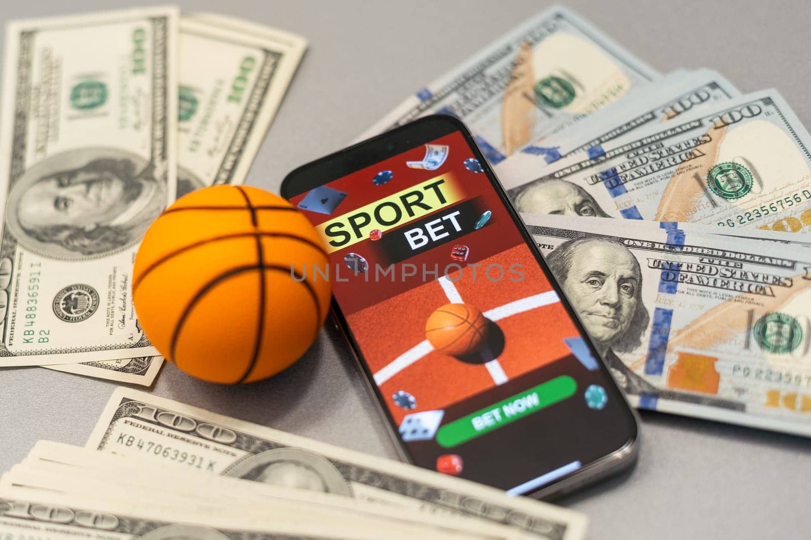 Smartphone with gambling mobile application and basketball ball with money close-up. Sport and betting concept. High quality photo