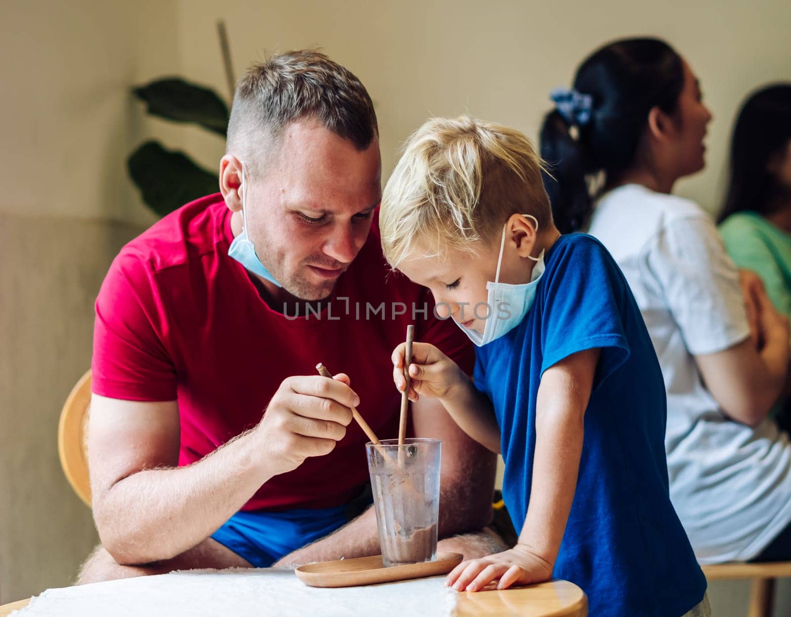 Father and son eat chocolate dessert with spoons in Cafe. Spending time together. Sweet tooth. Happy childhood.