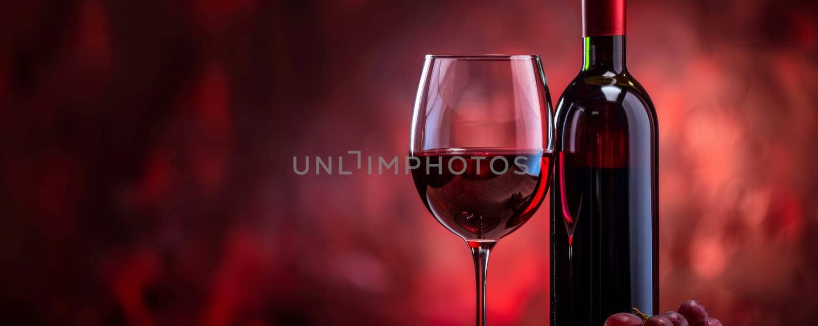 A glass filled with red wine sits beside a sleek bottle of wine on a wooden table. The deep red color of the wine contrasts with the clear glass.