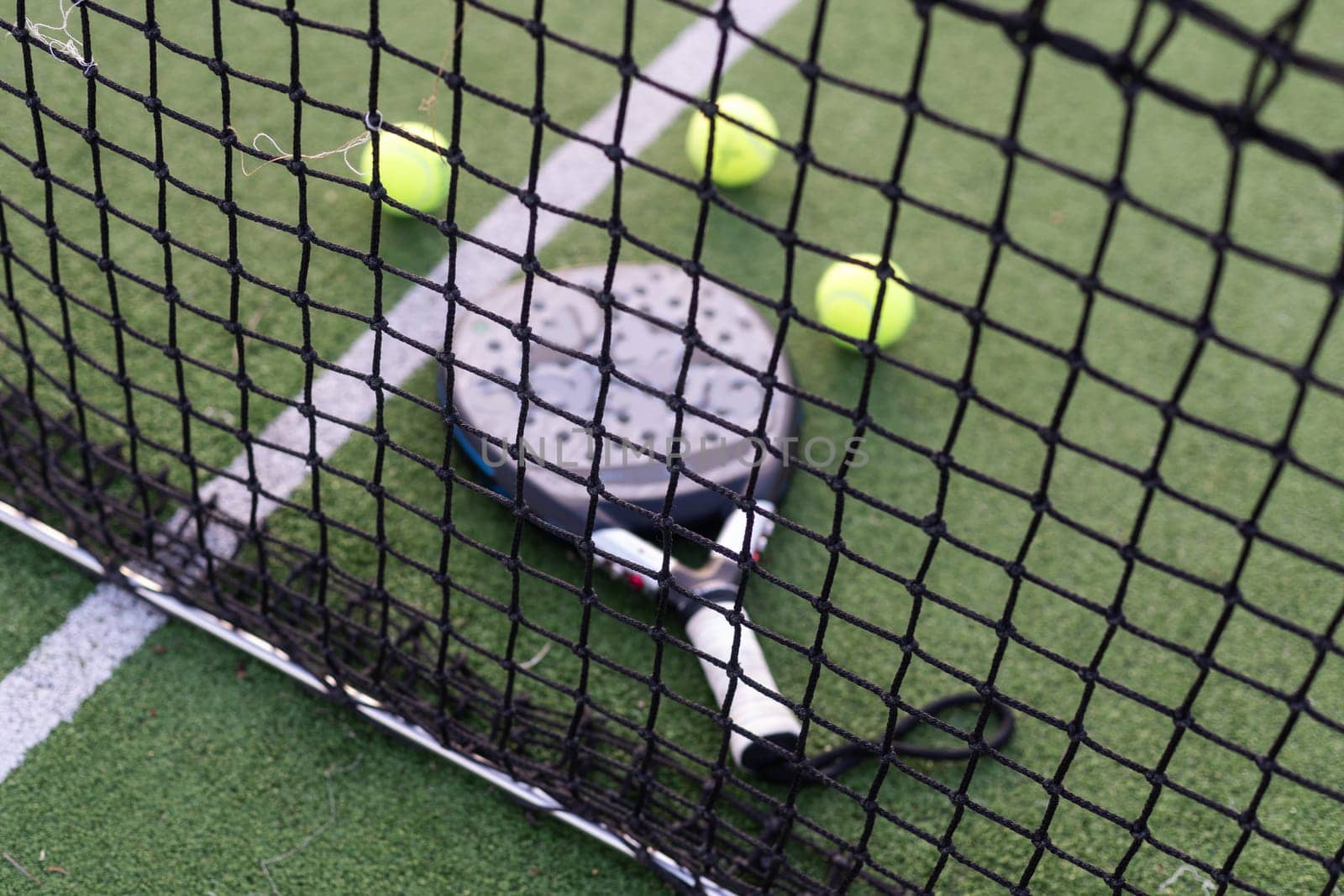 Paddle tennis racket, ball and net on the grass . High quality photo