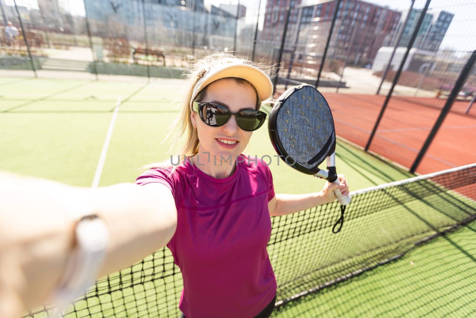 Active young woman trying to beat the ball by Padel racket while playing tennis in the court by Andelov13