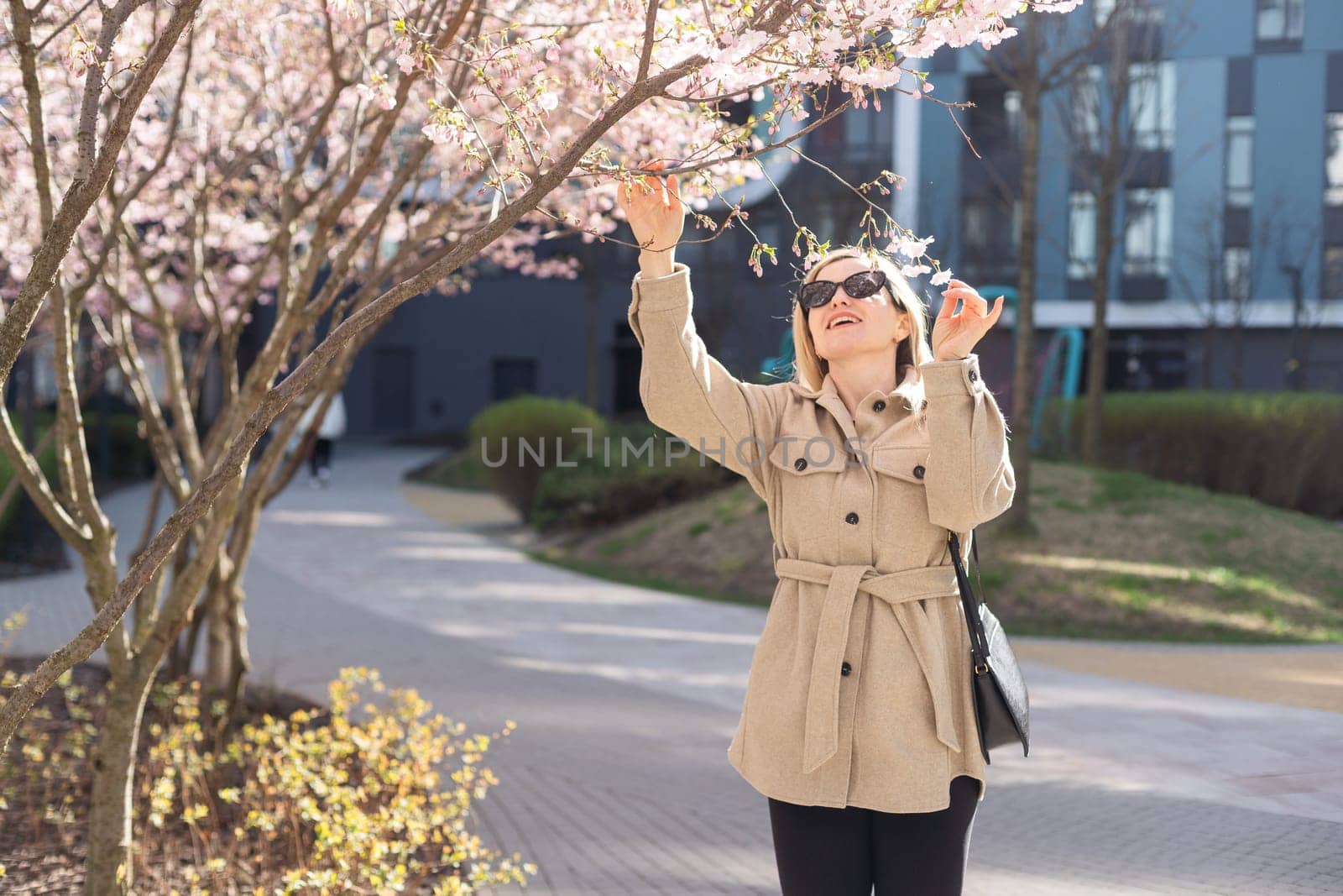 women is taking picture of blossoming cherry on mobile phone on street in spring. High quality photo