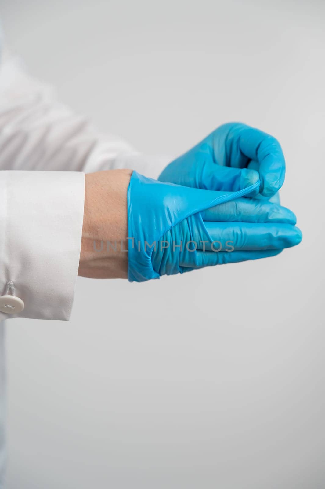 Doctor takes off latex gloves on a white background. Vertical photo