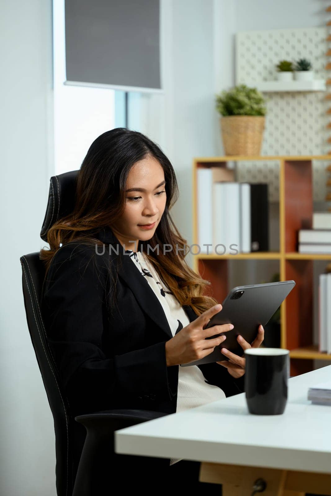 Portrait of gorgeous businesswoman sitting at her office desk and using digital tablet by prathanchorruangsak