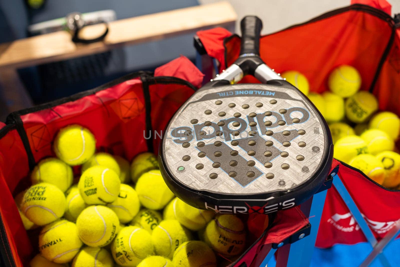 Kyiv, Ukraine, April 18, 2024. Black professional paddle tennis racket and ball with natural lighting on blue background. Horizontal sport theme poster, greeting cards, headers, website and app. High quality photo