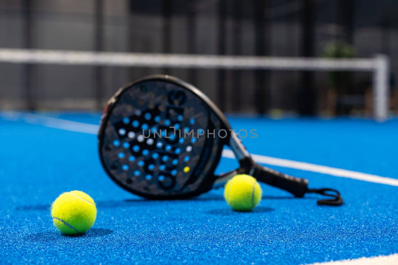 Kyiv, Ukraine, April 18, 2024. Black professional paddle tennis racket and ball with natural lighting on blue background. Horizontal sport theme poster, greeting cards, headers, website and app. High quality photo