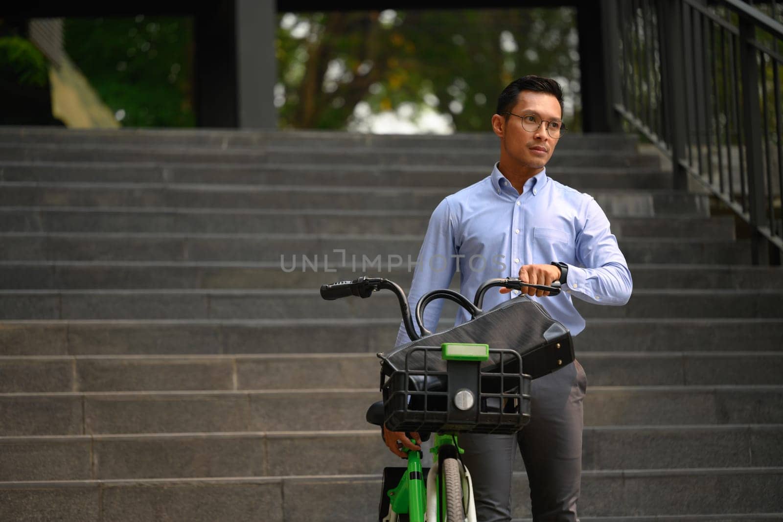 Shot of millennial businessman pushing bike on the street city. Business and city life concept.