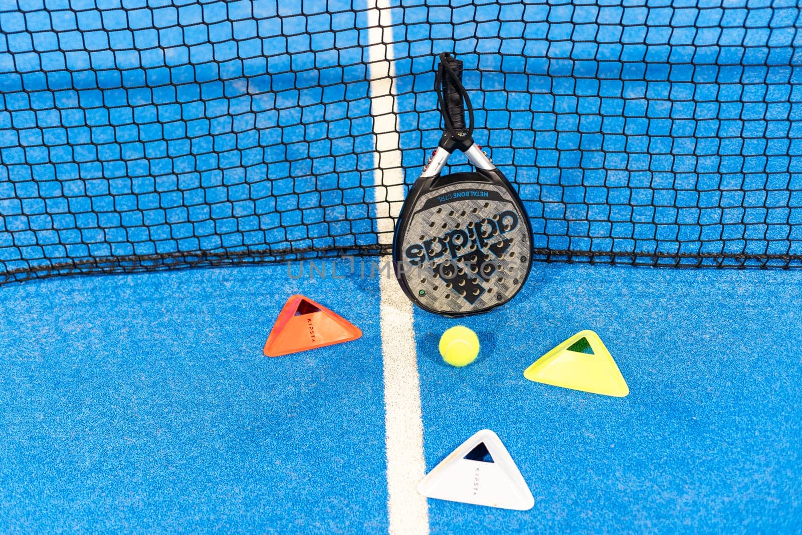 Kyiv, Ukraine, April 18, 2024. Black professional paddle tennis racket and ball with natural lighting on blue background. Horizontal sport theme poster, greeting cards, headers, website and app. High quality photo