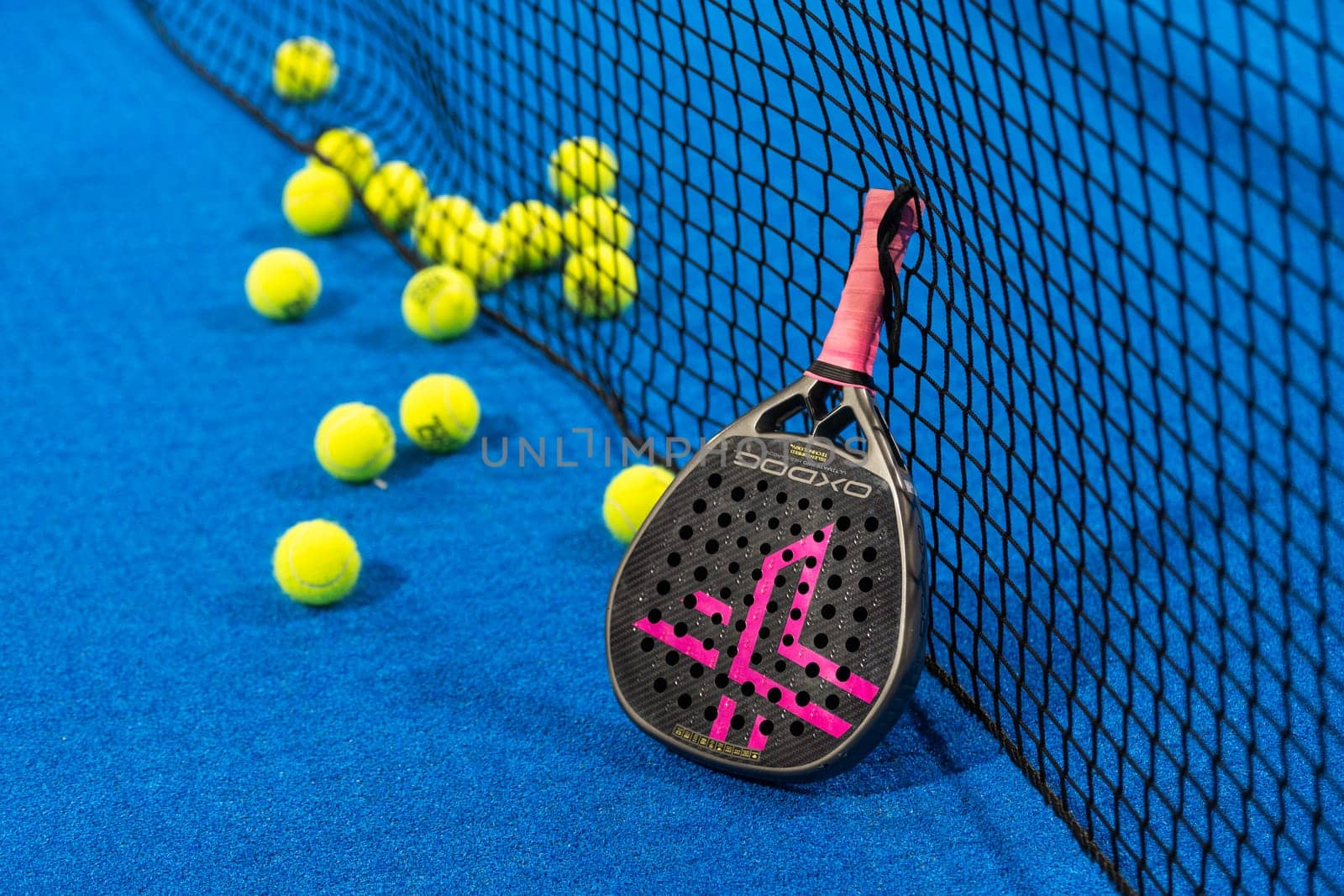 Kyiv, Ukraine, April 18, 2024. Black professional paddle tennis racket and ball with natural lighting on blue background. Horizontal sport theme poster, greeting cards, headers, website and app. High quality photo