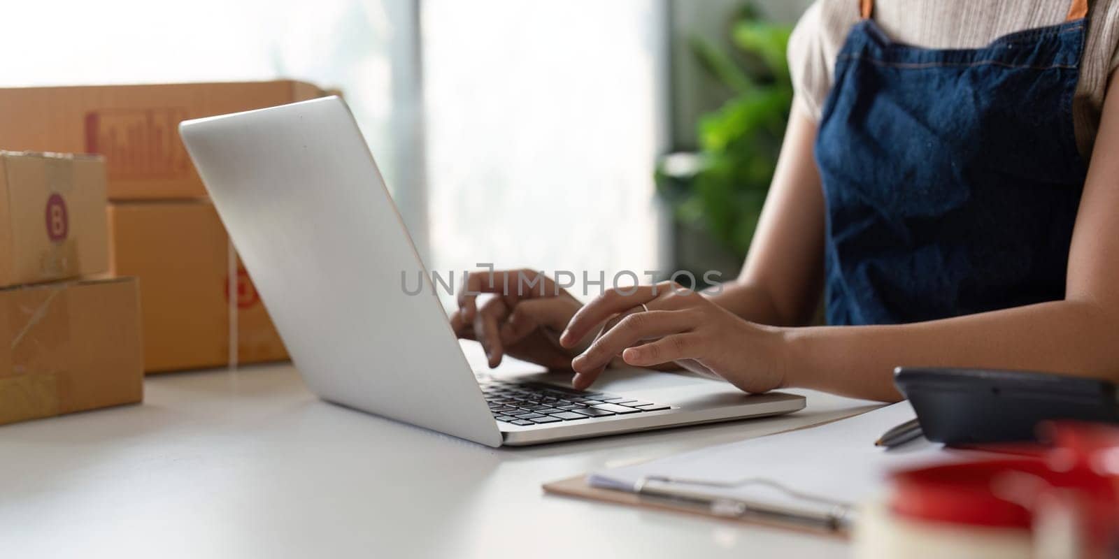 Woman in an online store check the customer address and package information on the laptop. Online shopping concept.
