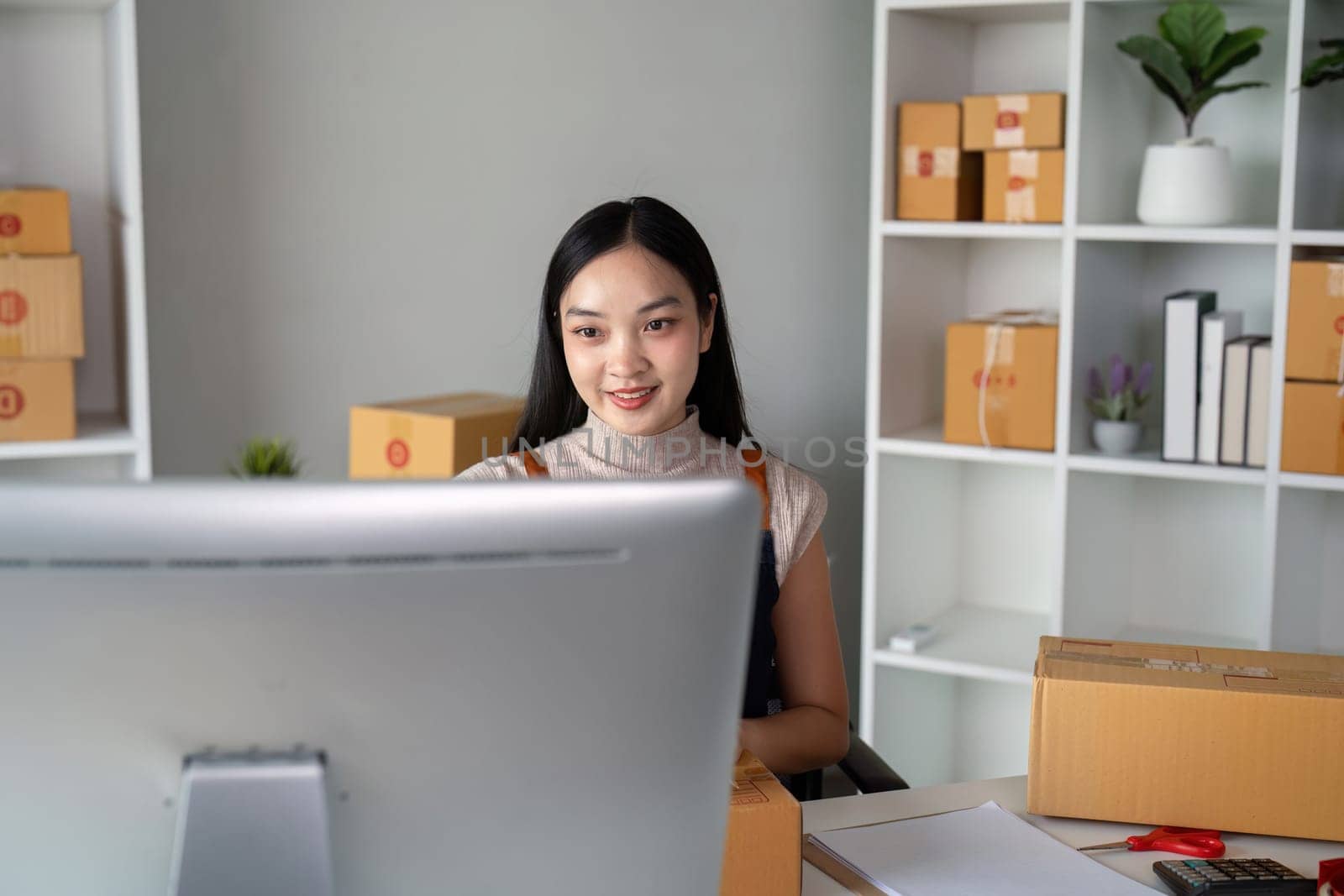 Young business woman asian working online ecommerce shopping at her shop. Young woman sell prepare parcel box of product for deliver to customer. Online selling.