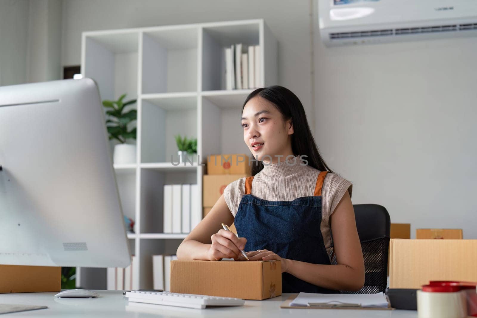 Young business woman asian working online ecommerce shopping at her shop. Young woman sell prepare parcel box of product for deliver to customer. Online selling by nateemee