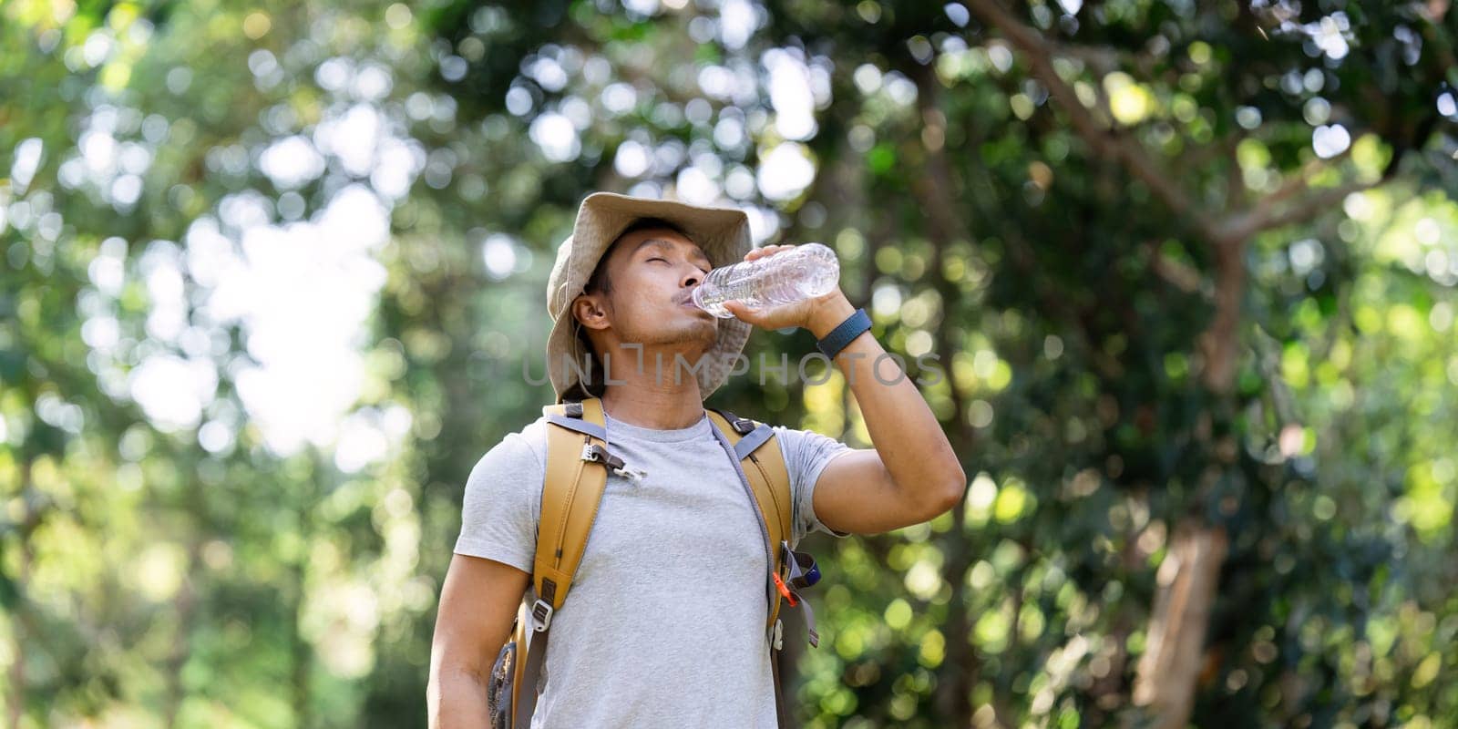 Traveler hiking man carrying a backpack on the back and walking in national park. man asian is rest by drink water by itchaznong