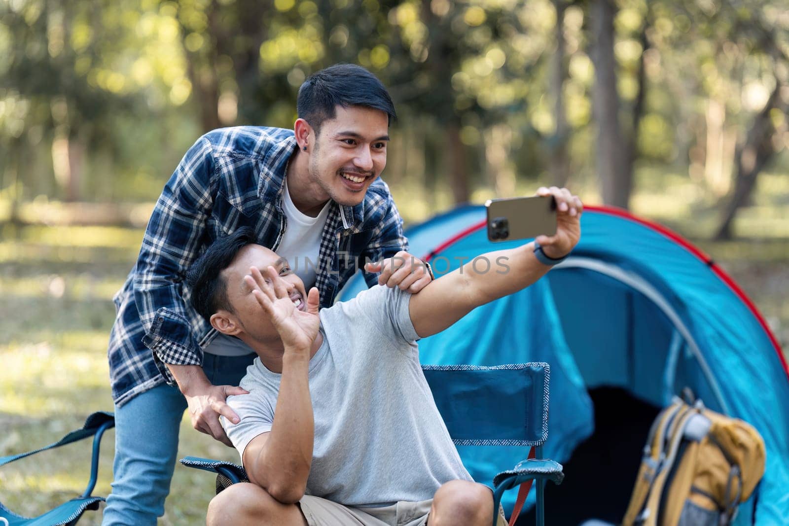 LGBTQIA Gay couple camping together in woods for holidays and relax together at the weekend.