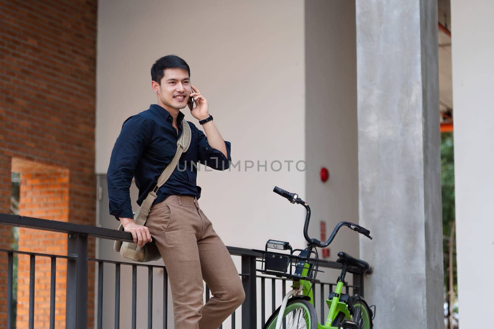 young asian businessman using mobile while walking in the street in downtown of modern city.