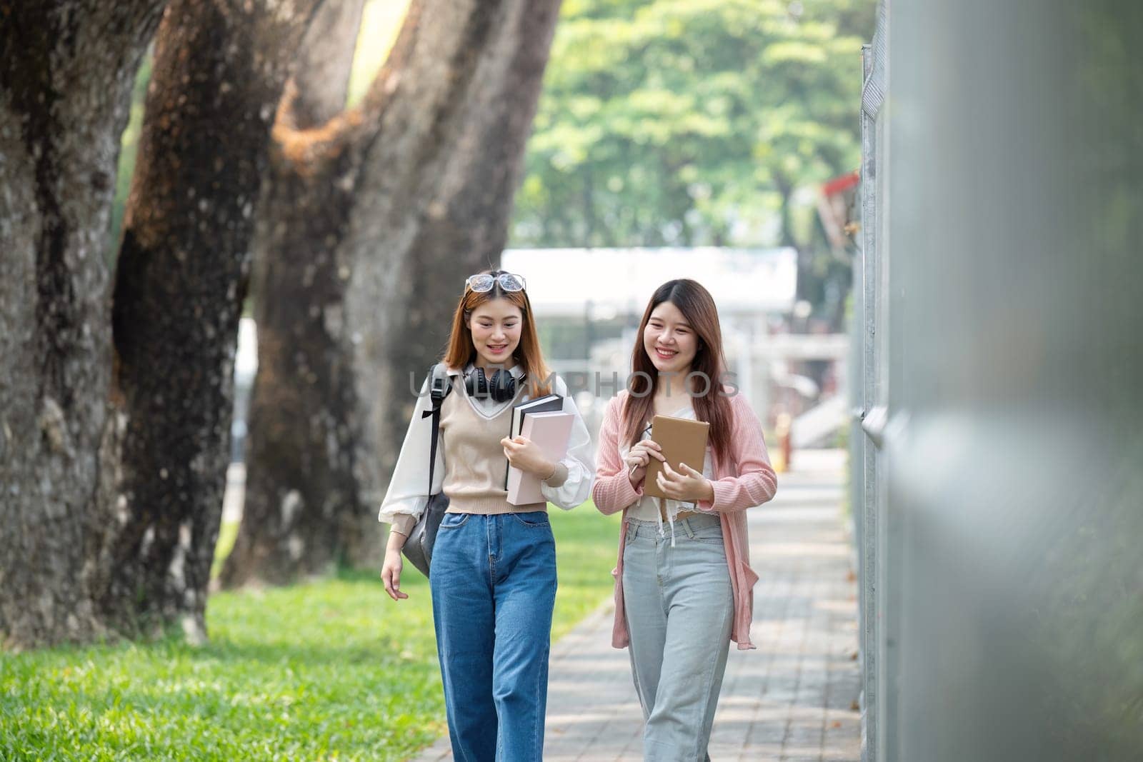 University student girl friends with learning book college while walking in campus by nateemee