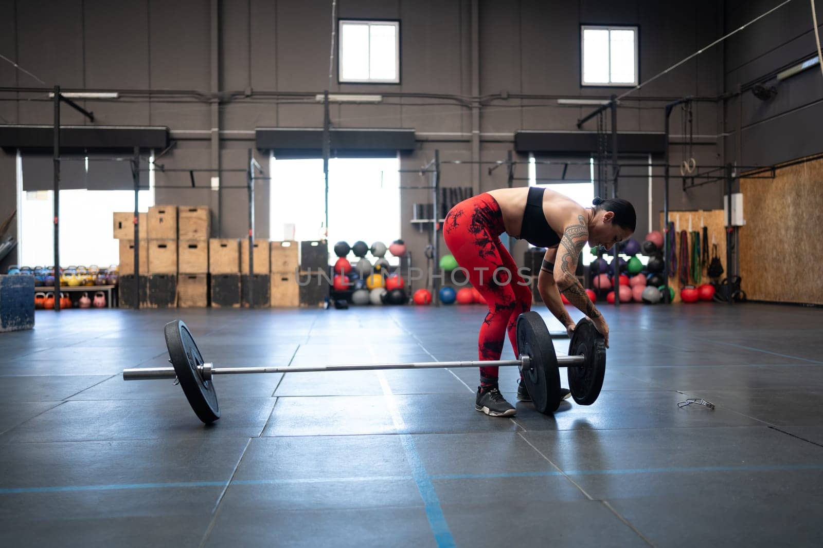 Horizontal photo with copy space of a mature fit woman preparing weights to dead-lifting in an empty gym