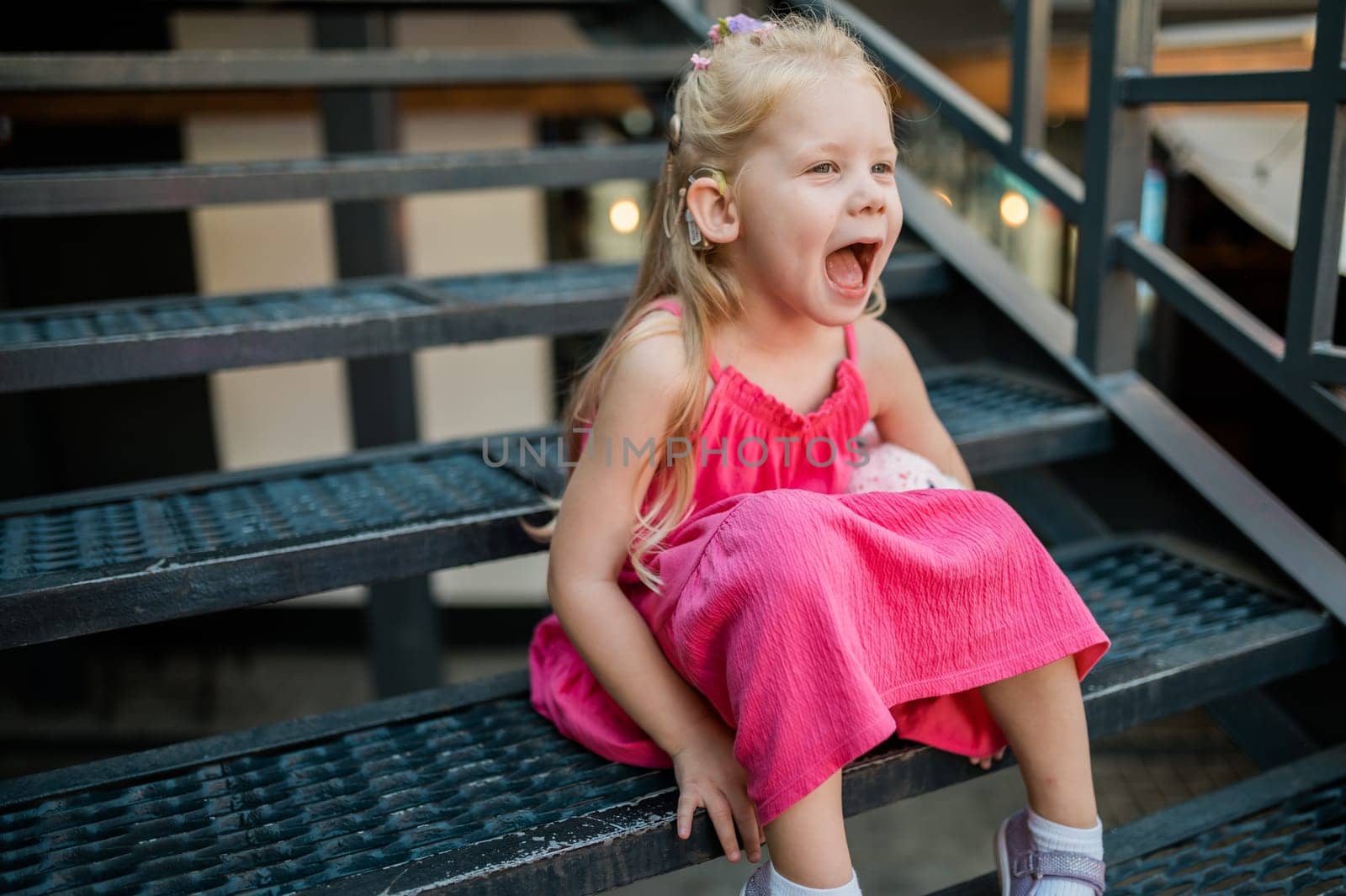 Child with hearing problem and cochlear implant dance in street, deaf kid began to hear. Hearing loss in childhood and treatment concept. Copy space and empty place for text.