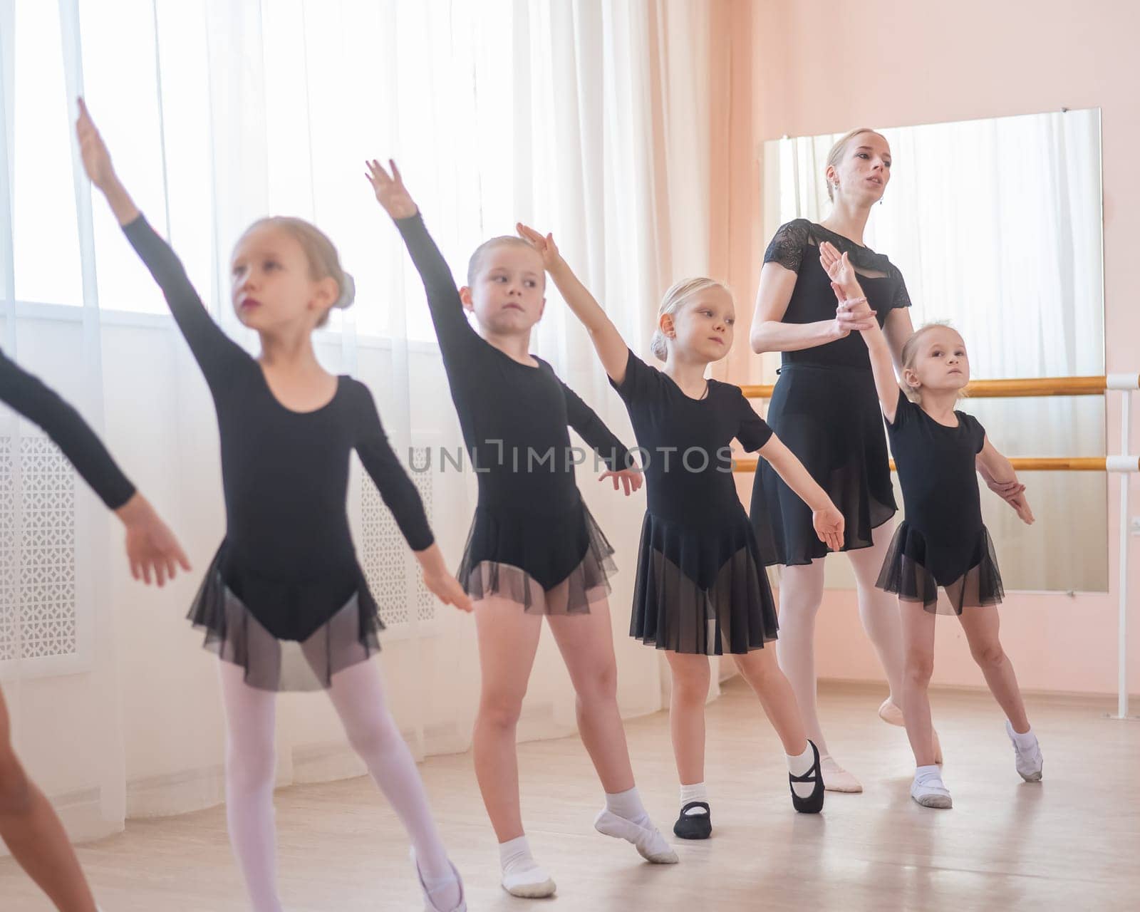 Children's ballet school. Caucasian woman teaching ballet to little girls