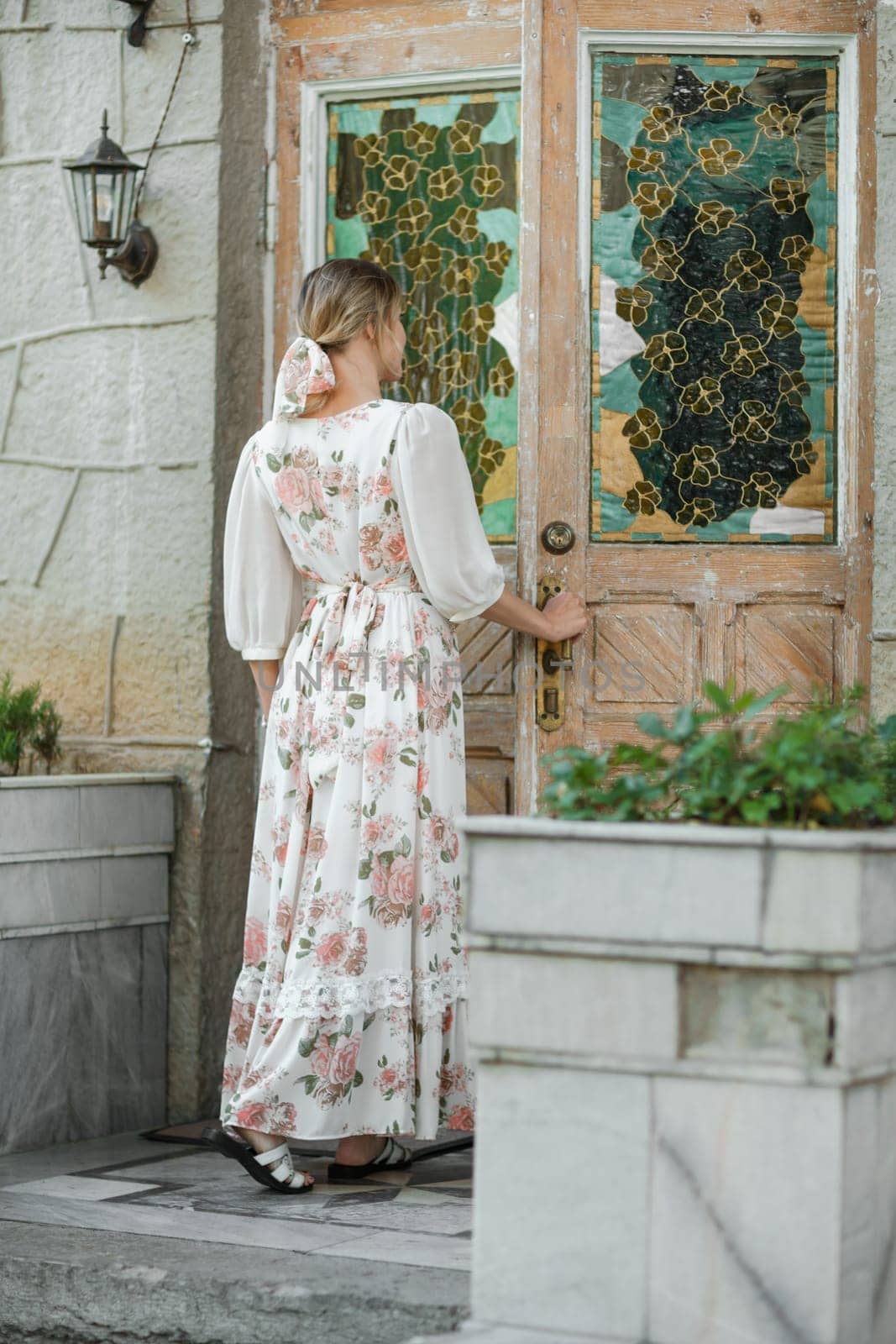 a woman in a flower dress opens the door to the house.