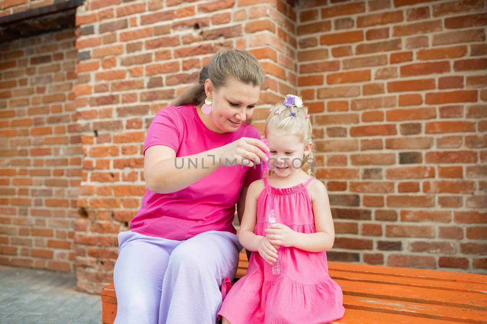 Deaf child with cochlear implant for hearing audio and aid for impairment having fun and laughs with mother outdoor in summer. Sound fitting device to help with communication listening and interaction.