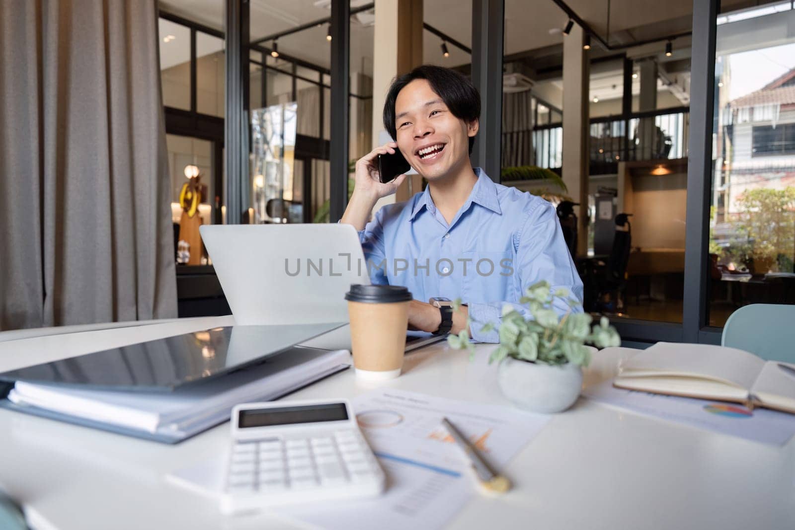 Business man asian discussing a new project with his client on the phone. business man working on a laptop in office.