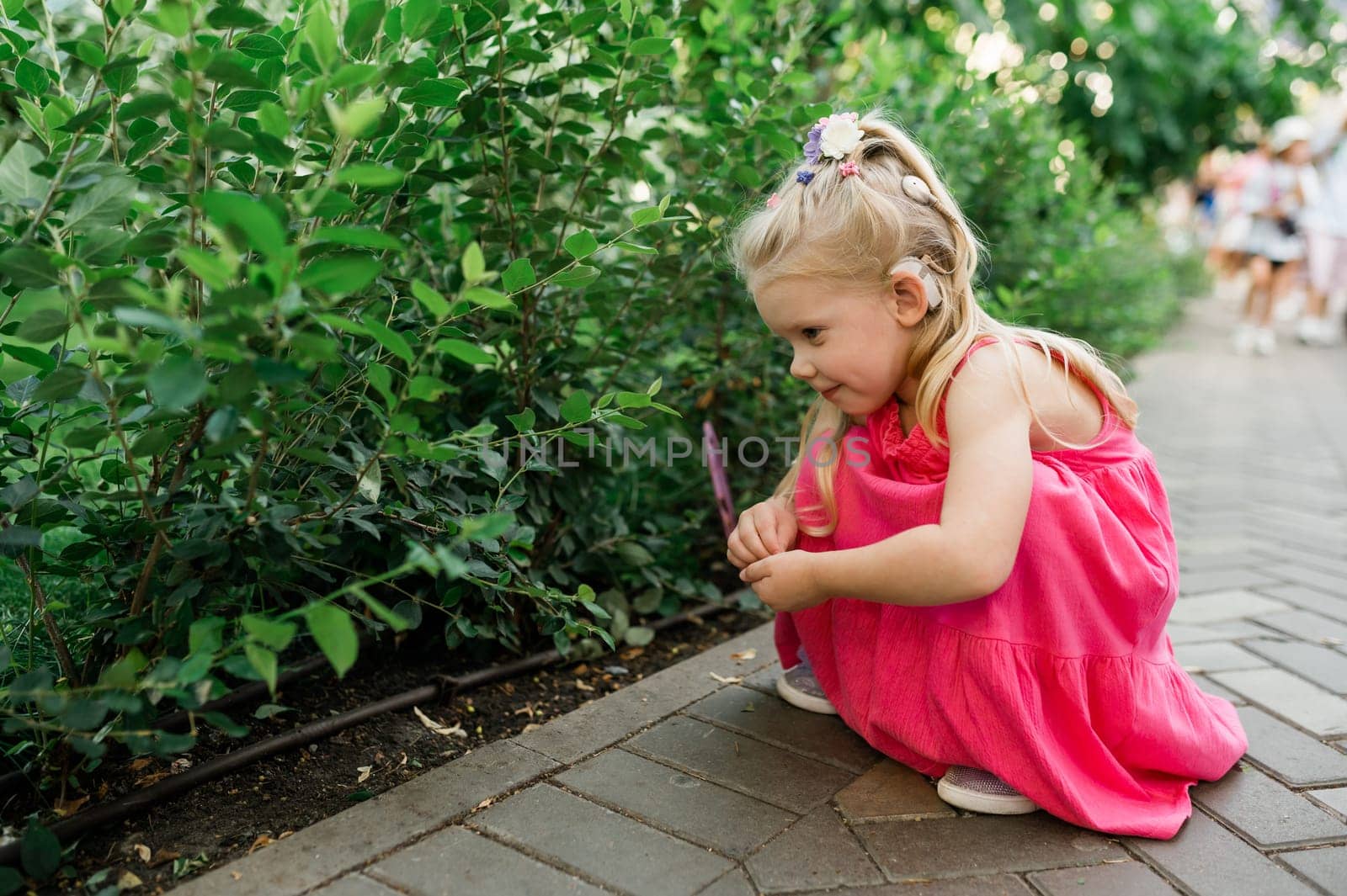 Child girl with hearing aids and cochlear implants having fun outdoor speak and playing. Copy space and empty place for advertising.