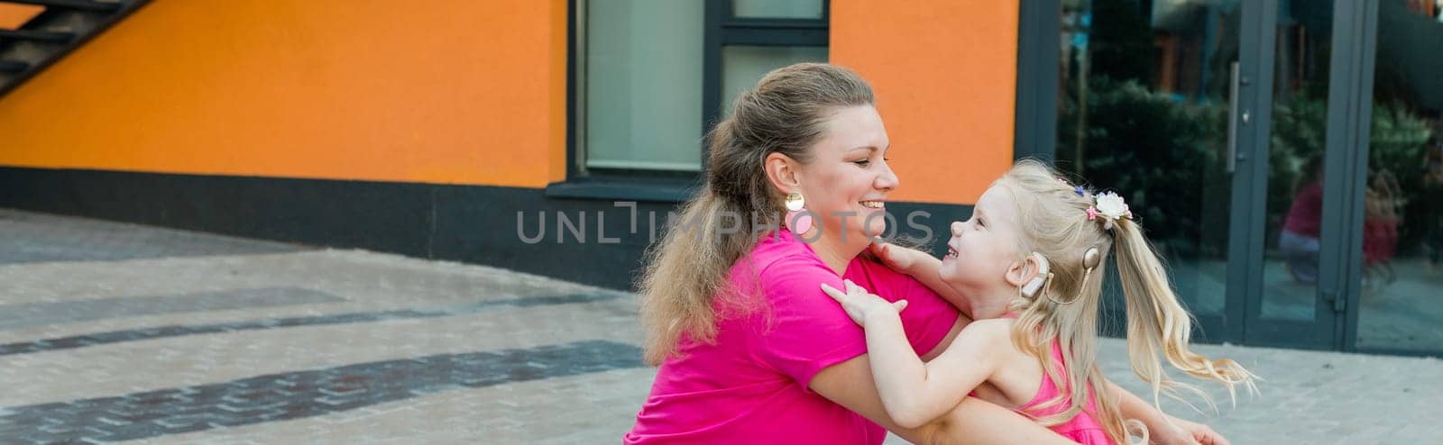 Banner Child girl with cochlear implant with her mother spend time outdoor. Hear impairment and deaf community concept. Deaf and health concept. Disability and inclusion. Copy space by Satura86