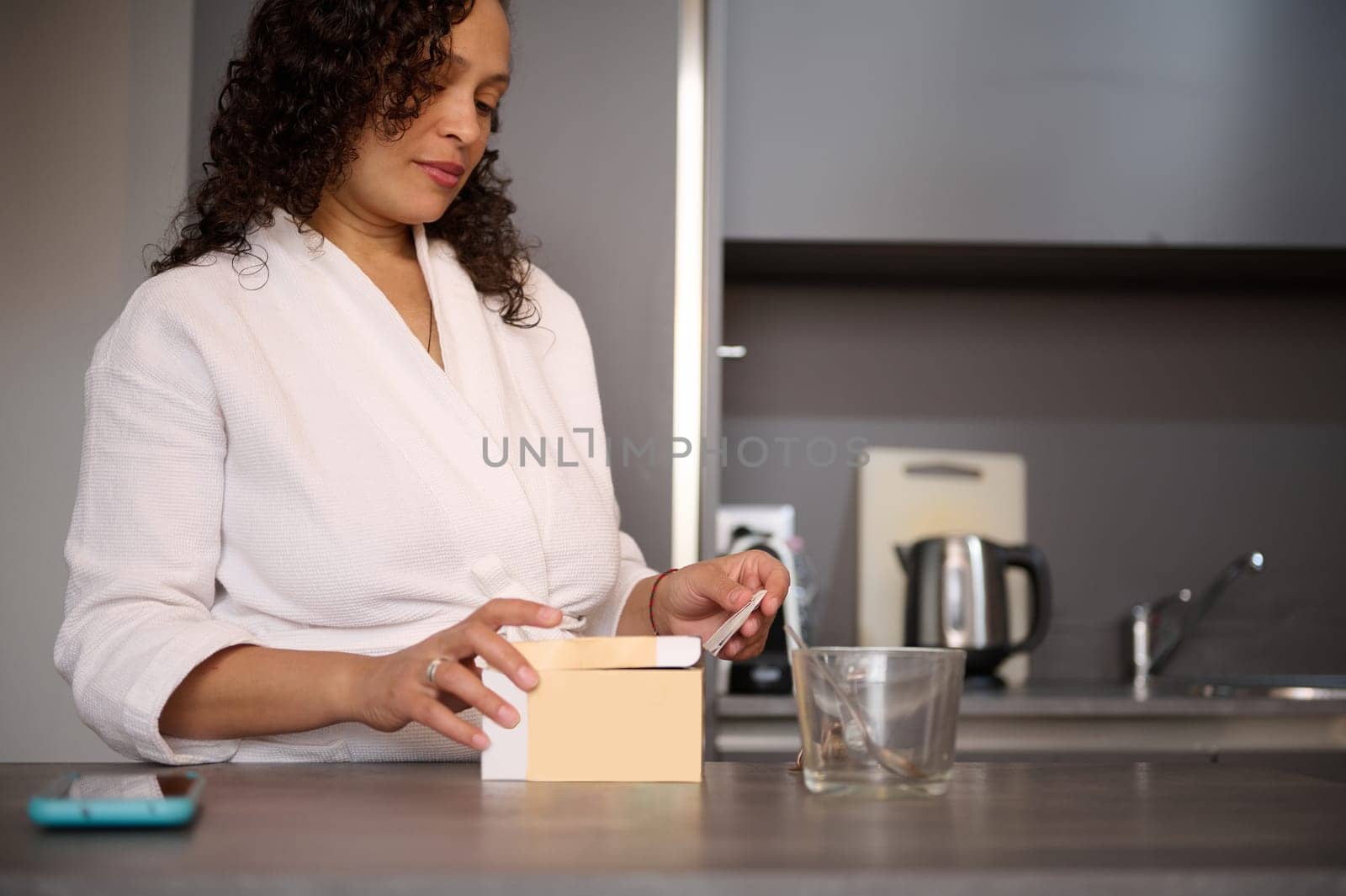 Charming young woman at home kitchen, preparing hot drink for breakfast