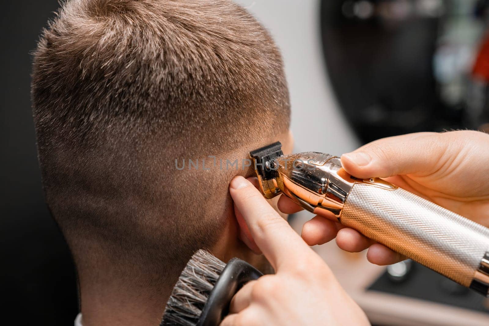 Barber shaves male client hair with trimmer in barbershop by vladimka