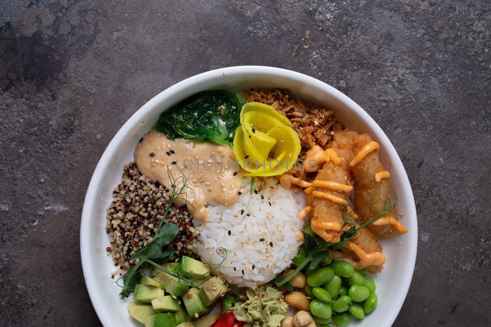 Healthy poke bowl with avocado, edamame, cucumber, carrots, salmon sesame ginger dressing. Fresh, delicious meal.