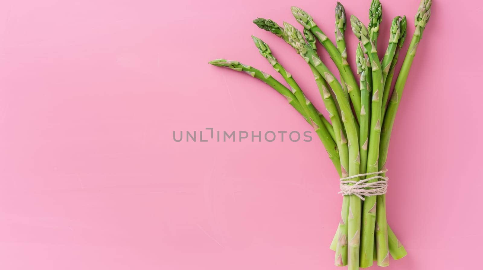 Bundle of asparagus on pink background.